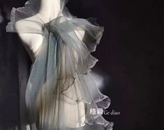 a mannequin is dressed in grey and white sheer fabric with ruffles