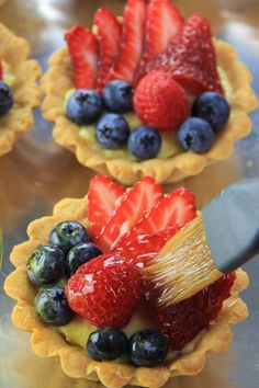 fruit tarts with strawberries, blueberries and raspberries on them are ready to be eaten