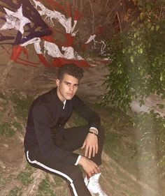 a young man is sitting on the ground in front of an american flag painted wall