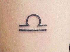 a small tattoo on the side of a woman's leg with an libra symbol