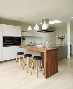 a kitchen with an island and stools in front of the counter top that has three lights hanging from it