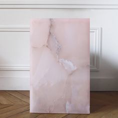 a pink marble block sitting on top of a wooden floor next to a white wall