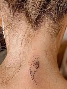 a woman's back neck with a small tattoo on the left side of her neck