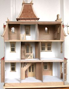 a wooden doll house with multiple floors and windows