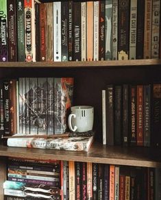 a book shelf filled with lots of books next to a coffee mug and other items