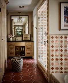 a bathroom with red tile flooring and wooden cabinetry next to a walk in shower