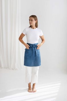 a woman standing in front of a white backdrop wearing a blue denim skirt and white t - shirt