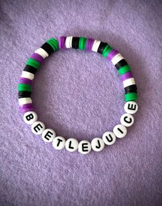 a beaded bracelet with the words believe spelled in white and green beads on a purple background