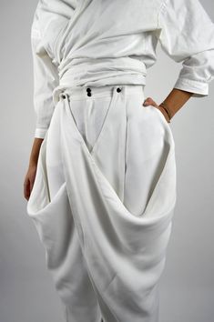 Made in FranceProduct description :- Very wide white pants,- High waist,- Invisible pockets and back darts,- Panels on the sides that attach to the belt or that can be left hanging,- Closed with a zip fly and a metal snap button.The Balmorra Pant is caracterized and formed delicately bu light, free and fluid curves. The pant recalls the inspirations of travel to which the Louise Marcaud brand attaches itself by adding its own touch of minimalism with fine and clean lines. Bold, lightweight trous Wide White Pants, Sarouel Pants, Unique Pants, Illustration Fashion Design, Clothing Details, Fashion Hacks Clothes, Pants Design, Fashion Design Clothes, Pants Pattern