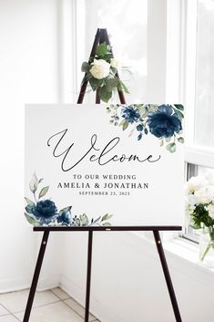 a welcome sign for a baby shower with flowers and greenery on the easel