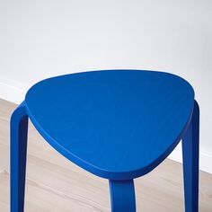 a blue table sitting on top of a hard wood floor next to a white wall