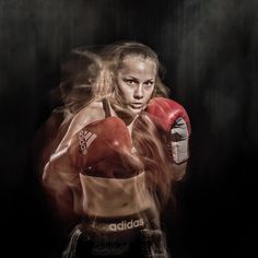 a woman wearing red boxing gloves and holding a punching mitt