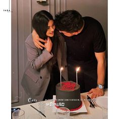 a man and woman standing in front of a cake with candles