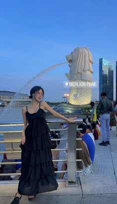 a woman in a long black dress standing next to a fountain