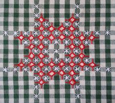 a close up of a piece of fabric with red and white flowers on green and white checkerboard