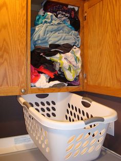 a white laundry basket sitting on top of a dryer in a kitchen next to wooden cabinets