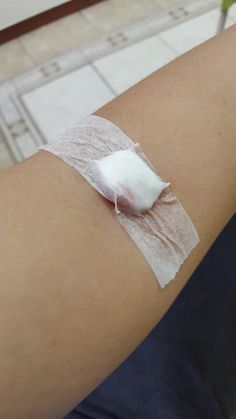 a woman's arm with bandages on it and a piece of paper taped to the side