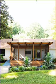 a small house sitting in the middle of a lush green yard with trees and bushes