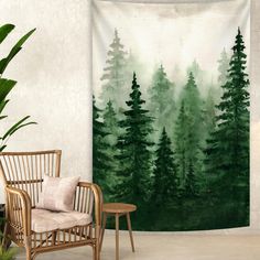 a green forest tapestry hanging on a wall next to a chair and potted plant