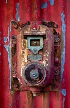 an old rusted metal object on the side of a red and blue building with peeling paint