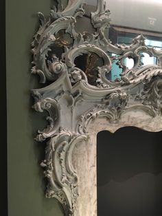 an ornate white mirror hanging on the wall