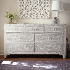 a white dresser sitting in front of a lamp