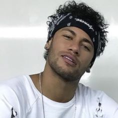 a man wearing a white shirt and black headband with his eyes closed while sitting in front of a wall