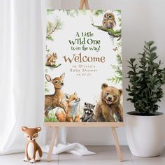 an easel with a welcome sign on it next to a potted plant and stuffed animals