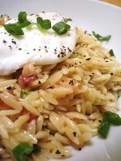 a white plate topped with pasta and an egg