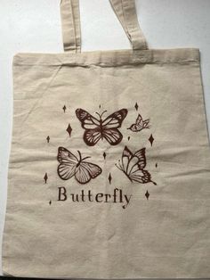 a tote bag with butterflies on it and the words butterfly written in brown ink