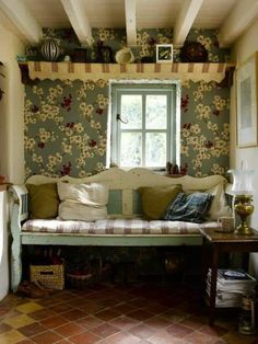 a living room with a couch, table and window in the corner next to it