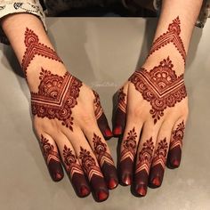 two hands with henna designs on them, one is red and the other is white