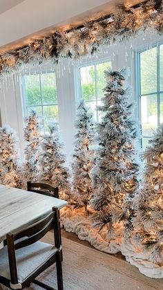 a dining room decorated for christmas with white trees