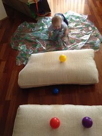 a toddler playing with balls on the floor in front of a pillow and chair