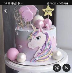 a unicorn cake with balloons and stars on top