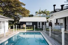 an empty swimming pool in the middle of a backyard with white siding and wood flooring