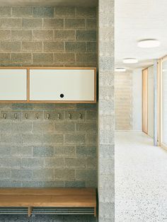 a bench sitting in front of a brick wall next to a doorway with glass doors