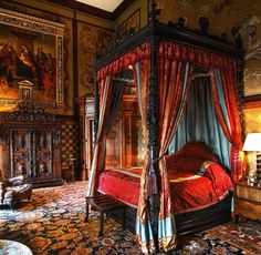 an ornate bedroom with red bedding and paintings on the walls