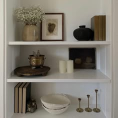 a white shelf filled with books and vases on top of it's shelves