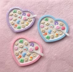 two heart shaped trays filled with cookies and candies on top of a pink blanket