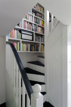 there is a staircase with bookshelves on the wall and black and white carpet