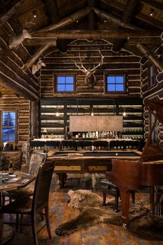 an old log cabin with a grand piano in the foreground and deer heads on the wall