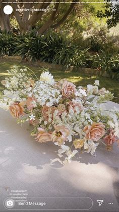 a bouquet of flowers sitting on top of a white cloth covered table next to trees