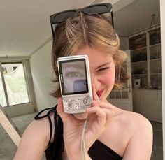 a woman holding up a camera to take a photo with her cell phone in front of her face