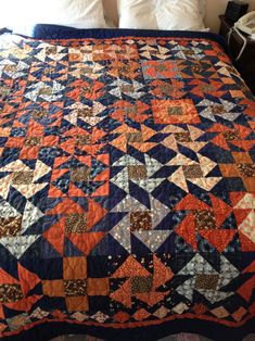 a bed with a blue and orange quilt on it