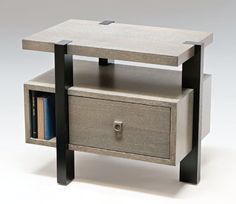 an end table with two drawers and a book shelf on one side that has books in it