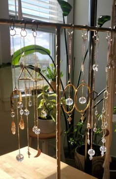 a wooden table topped with lots of gold chains and dangling glass beads next to a potted plant