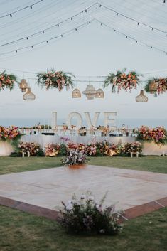 an outdoor wedding setup with flowers and hanging lights