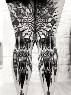 black and white photograph of legs with tattoo designs on the bottom part of each leg