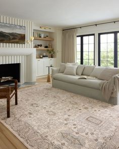 a living room filled with furniture and a large rug on top of a hard wood floor